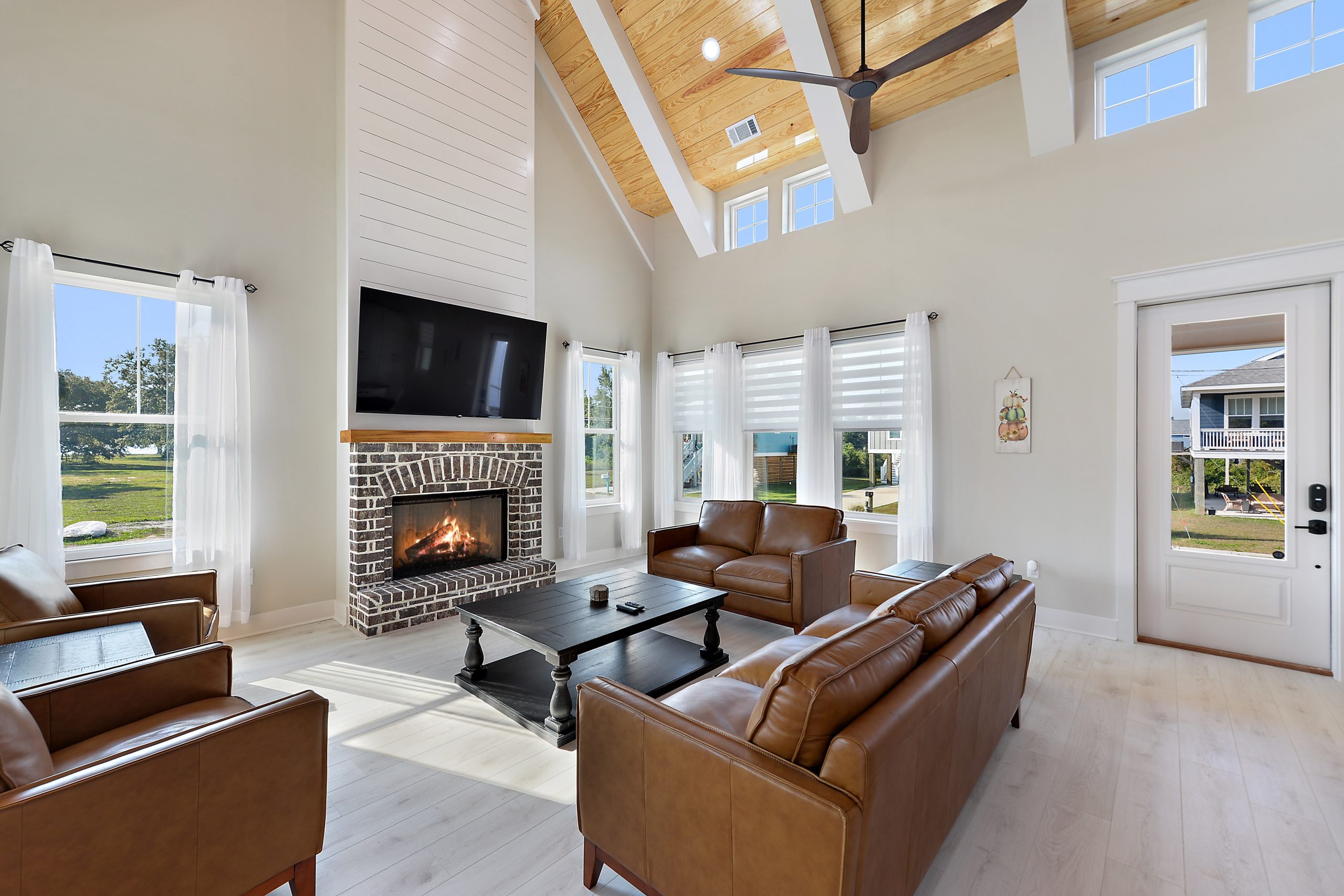 Living room with a brick fireplace and vaulted ceiling in a custom coastal farmhouse by Full Armour Homes