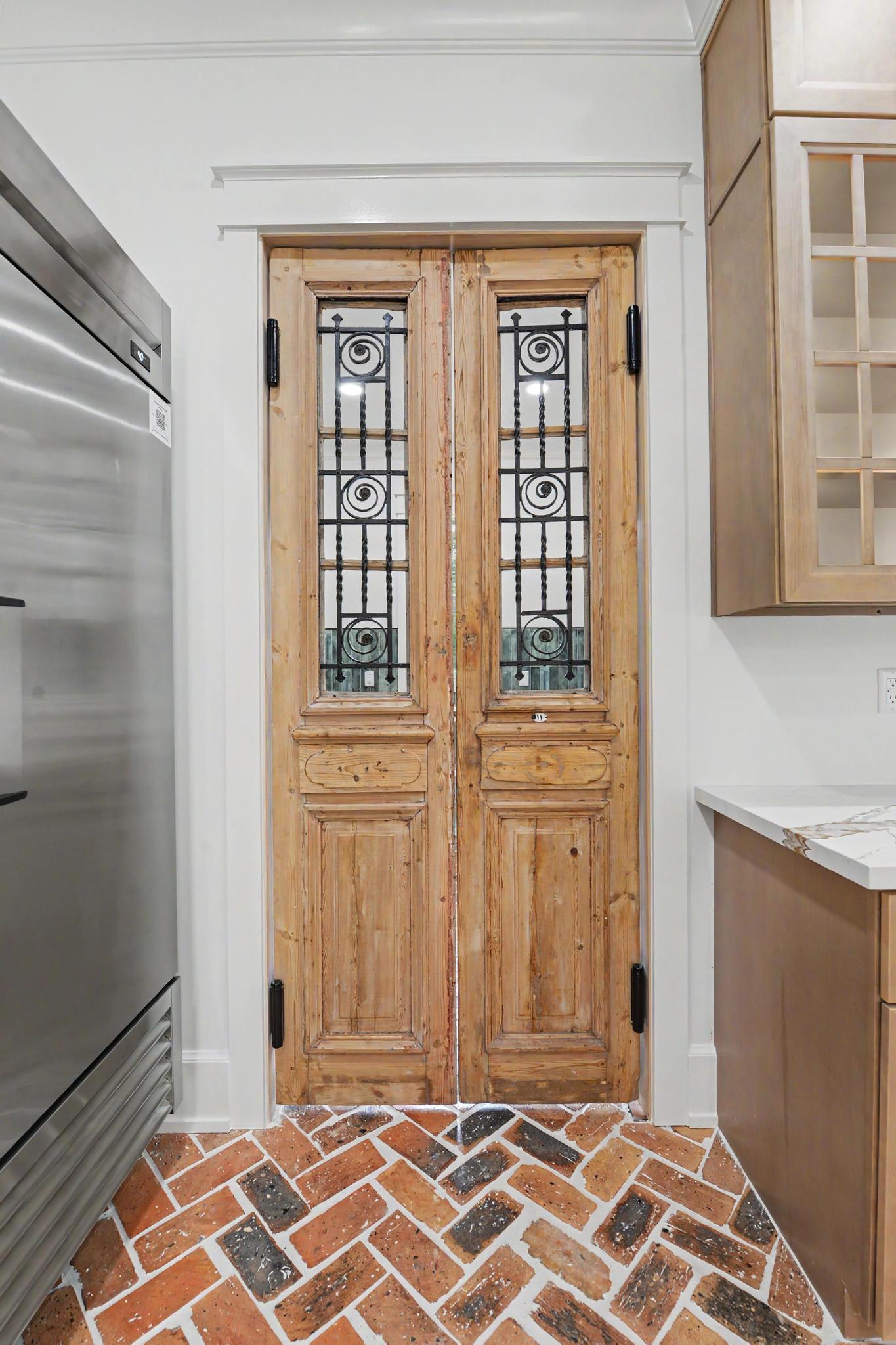Antique iron pantry doors over a brick herringbone floor in a custom home by Full Armour Homes