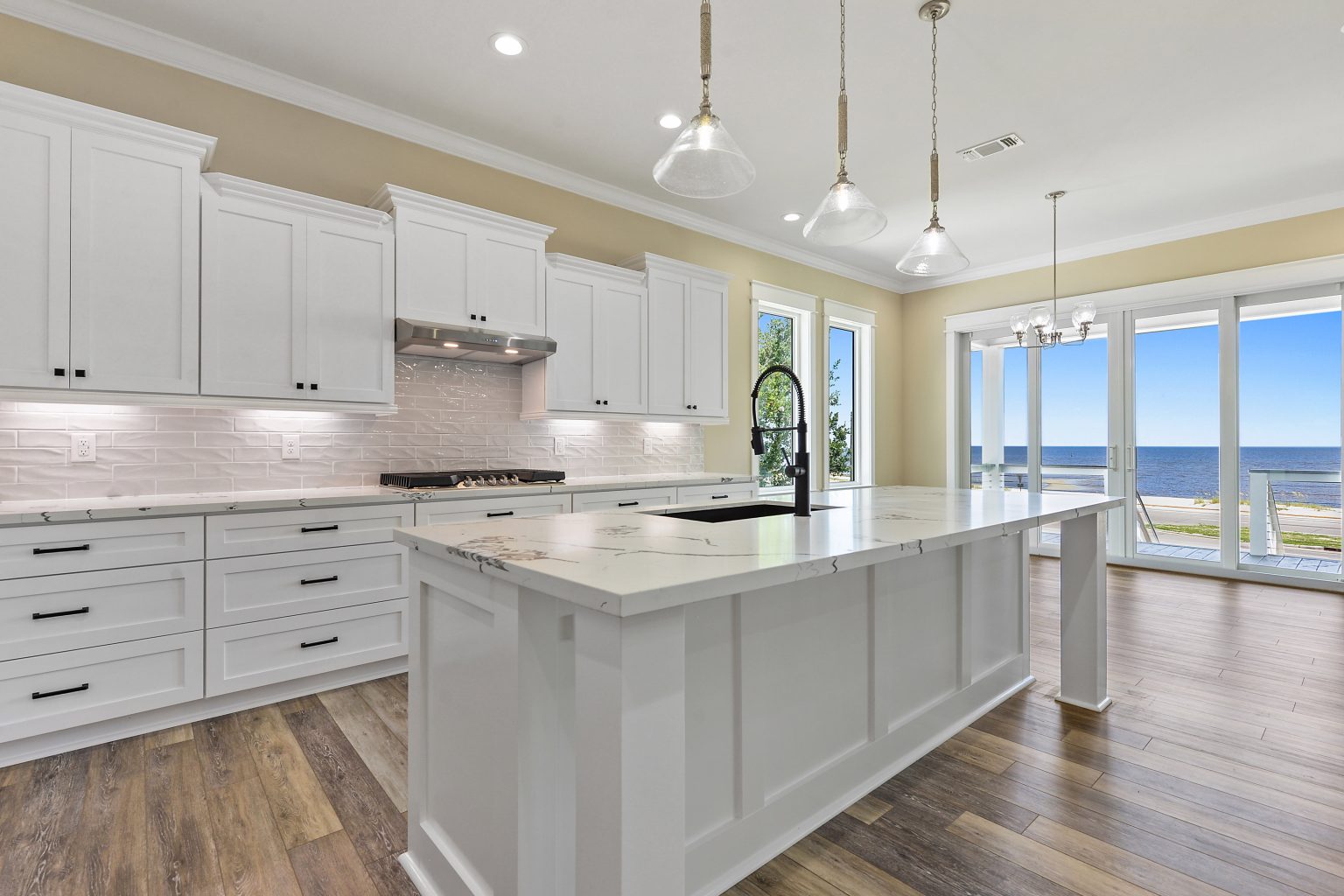 Kitchen with a waterfall island and water view in a custom waterfront raised home by Full Armour Homes